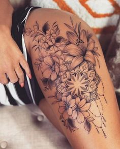 a woman's thigh with flowers on it and an intricate design in the middle