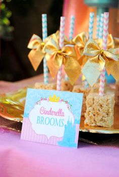 a table topped with cake and candles on top of a pink cloth covered tablecloth