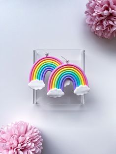 two rainbows are sitting in front of pink flowers and paper pom poms