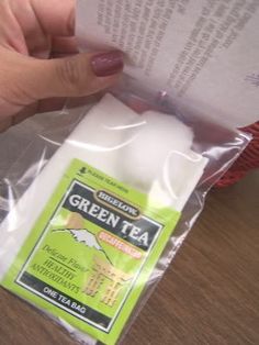 a person is holding up a green tea packet