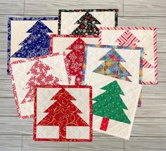 six quilted christmas tree coasters on a wood floor with white boards in the background