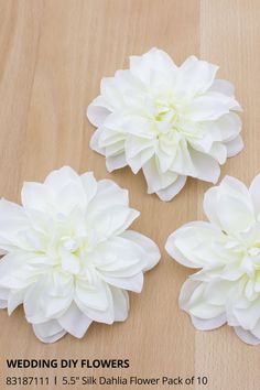 three white flowers sitting on top of a wooden table