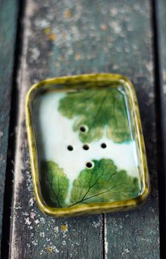 a green and white square object sitting on top of a wooden table with holes in it