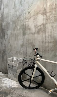 a bicycle parked against a wall with stacks of bricks