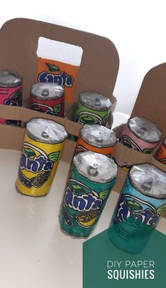 six cans of canned soda sitting on top of a table next to a cardboard box