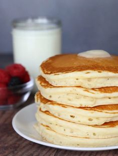 a stack of pancakes sitting on top of a white plate next to a glass of milk