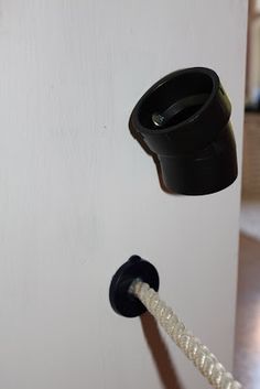 an electrical outlet attached to a white wall with a black plug in the middle and a cord running through it