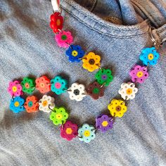 a necklace made out of buttons and flowers on top of a blue jean shirt with a pair of scissors next to it