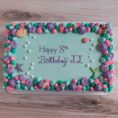 a birthday cake decorated with sea shells and seashells on a wooden table top