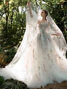 a woman wearing a wedding dress and veil in the woods