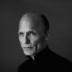 black and white photo of an older man with blue eyes looking at the camera while wearing a polo shirt