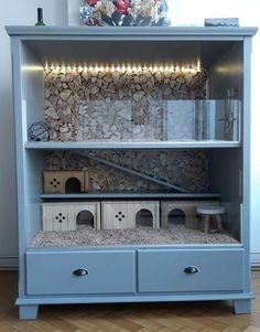 a blue bookcase with two drawers and some lights on the top, in front of a window