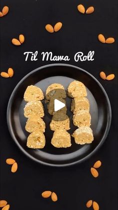 a black plate topped with pieces of food on top of a wooden table next to almonds