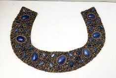 gorgeous piece for summer or winter wear Azeeza Khan luxury accessory collar add this to a black dress or jumpsuit to elevate it to a statement piece.  Beautiful colors and textures  In this piece  sewn beaded collar with 2 tiny hook and eye fastening hooks intricate hand done beadwork sewn on black fabric to create a collar blue cabochon stones, gold glass beads this piece is heavy weight.  perfect condition approx  17" inner measurement around neck *Due to the nature of vintage, there might be the occasional imperfection. I will do my best to describe any noticeable flaws. Although I take excellent care of the items I have, please remember they had a previous life. If you have any doubts about the appearance of an item -please don't hesitate to ask any questions that may concern you. Beaded Collar Necklace, Beaded Collar, Beaded Accessories, Gold Glass, Luxury Accessories, Collar Necklace, Hand Beading, Black Fabric, Beautiful Colors