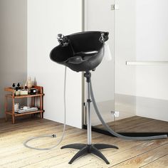 a black chair sitting on top of a wooden floor next to a shower head and hose