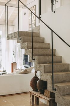 a living room with stairs and vases on the floor