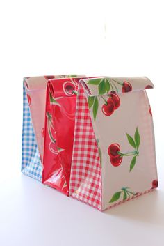 three bags with cherries and gingham checks on them are sitting next to each other