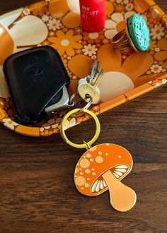 a cell phone and keychain sitting on a tray with flowered design,