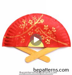 a red paper plate with gold designs on it and two wooden sticks sticking out of it