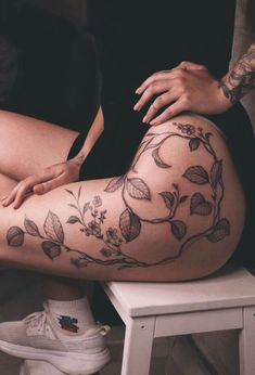 a woman is sitting on a stool with her legs crossed and tattoos on her body