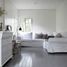 a living room with white furniture and wood floors