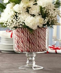 a christmas centerpiece with white flowers and red and white candy canes in it