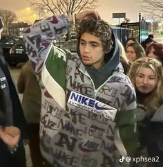 a group of young people standing around each other in front of a man wearing a nike jacket