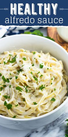 a white bowl filled with alfredo sauce on top of a marble counter topped with parsley