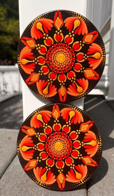 two orange and black plates sitting next to each other on top of a cement ground