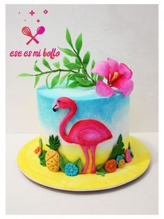 a birthday cake decorated with a pink flamingo and pineapples on a yellow plate