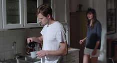 a man standing in a kitchen next to a woman