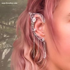 **Embrace the ethereal allure of elven grace with these enchanting Elven Bride Elf Ears by Elven Rose.** Crafted with love and meticulous attention to detail, these silver and white earrings embody the grace and allure of the elven realm. The delicate curves mimic the elegant shape of elven ears, while the intricate details capture the essence of elvish craftsmanship. Each earring delicately wraps around the earlobe, creating an enchanting and mystical aura. **Highlights - Handcrafted Excellence: Each pair is meticulously handcrafted using high-quality materials, ensuring both durability and exquisite craftsmanship. - Premium Materials: Made with non-tarnish silver-plated wire, Swarovski crystals, resin flowers, and Moonstone. - Fantasy-Inspired Design: The gleaming silver finish complemen