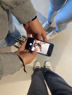 two people standing next to each other holding up their cell phones in front of them