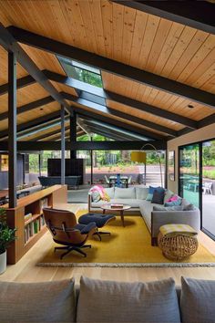 a living room with couches, chairs and tables under a roof that has wood paneling