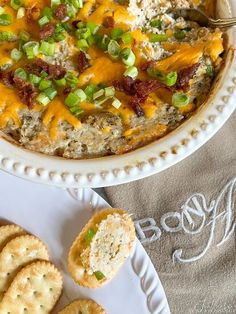 a bowl of dip with crackers and cheese on the side, next to crackers