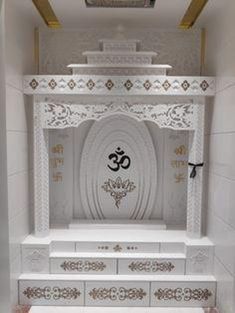 a white and gold decorated room with an om sign on the wall above the door