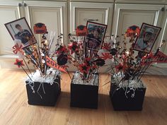 three black vases with red and white flowers in them on a wooden floor next to pictures