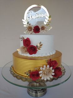 a three tiered cake with red flowers on the bottom and gold trimmings