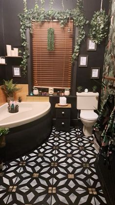 a black and white tiled bathroom with plants on the wall