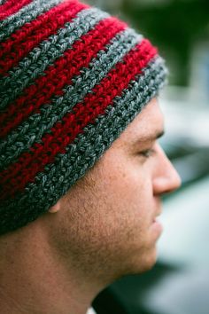 a close up of a man wearing a knitted hat with red and gray stripes