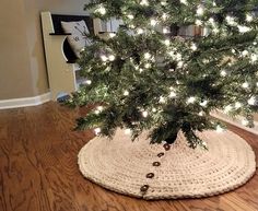 a small christmas tree in a crocheted pot holder with lights on the top