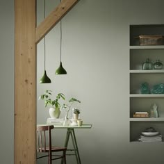 a dining room table with two green lamps hanging from it's ceiling