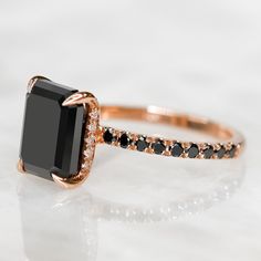 an engagement ring with black and white diamonds on it's sides, set in rose gold