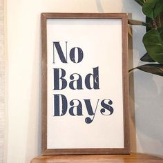 there is a framed poster with the words no bad days in black on it next to a potted plant