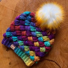 a multicolored knitted hat with a pom - pom on top