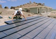 a man on top of a roof installing solar panels