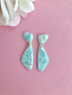 two pieces of blue stone sitting on top of a pink surface next to flowers and a white flower