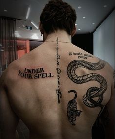 a man with a tattoo on his back and the words under your spell written in black ink