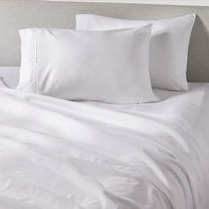 a bed with white sheets and pillows on it