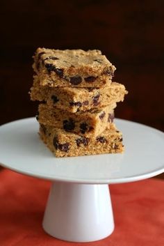 three cookies stacked on top of each other on a white cake plate with a red tablecloth